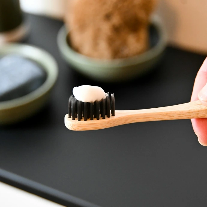 a person holding a toothbrush with a toothpaste on it